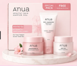 A K-beauty skincare set by Anua featuring the Niacinamide Brightening routine, including toner pads, serum, and moisture barrier cream in light pink packaging on a marble display tray.